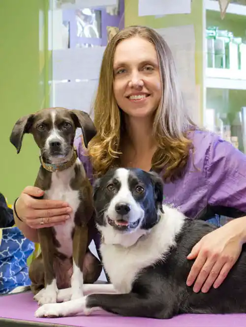 Erica, Co-owner of Green Dog Spa poses with two dogs.